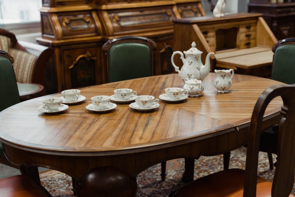 Antique wooden dining table with vintage tea set and chairs