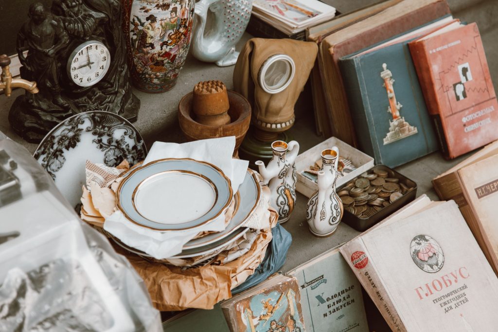 Vintage books, porcelain dishes, coins and antiques at a market stall